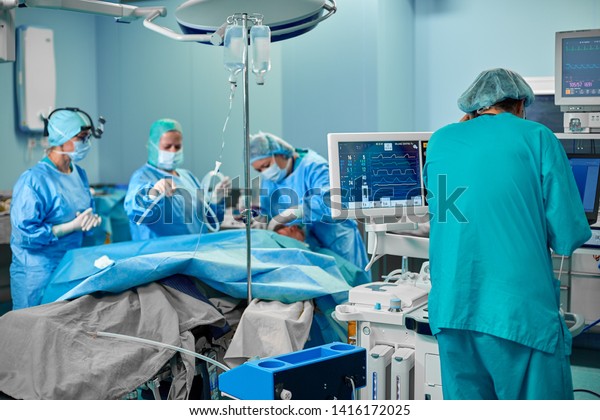 外科医の背景にぼかしたチームを持つ患者の心拍数を示す 病院手術救急室の心電図 の写真素材 今すぐ編集