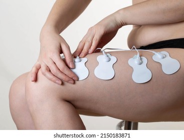 Electrodes of modern acupuncture and anti-cellulite massagers on the legs of a girl in problem areas. Home physiotherapy