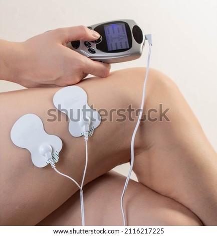 Electrodes of modern acupuncture and anti-cellulite massagers on the legs of a girl in problem areas. Home physiotherapy