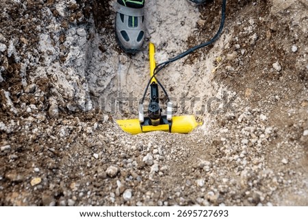 Electrofusion welding device cables. A coupling on a yellow polyethylene (PE) natural gas distribution pipe in the trench is joined to the main pipeline using electrofusion welding.