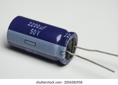 Electrolytic capacitor is an electronic component that function to temporarily store electric current. Blue electronic capacitor with polarity on white background isolated. Macro closeup shots.