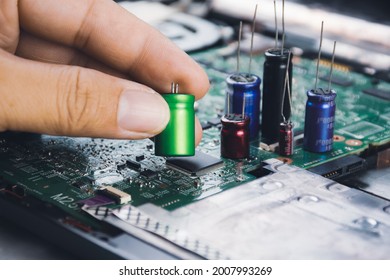Electrolytic capacitor in the hand with capacitor group placed on electronic circuit board