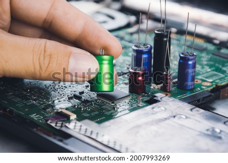 Electrolytic capacitor in the hand with capacitor group placed on electronic circuit board