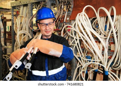 Electromechanic In Electrical Safety Gloves Holds Power Cable, Cabling Connection Of High Voltage Power Electric Line In Industrial Distribution Fuseboard.