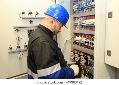 Electromechanic In Electrical Safety Gloves Holds Power Cable, Cabling Connection Of High Voltage Power Electric Line In Industrial Distribution Fuseboard.