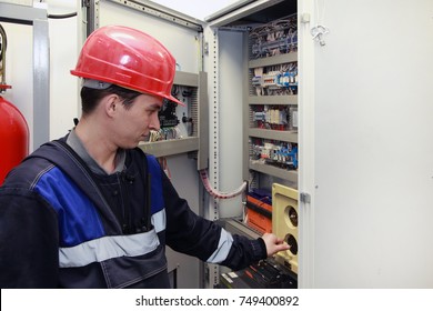 electromechanic in electrical safety gloves holds power cable, cabling connection of high voltage power electric line in industrial distribution fuseboard