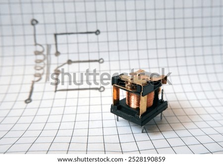 Electromechanical relay in front of the drawn circuit structure.  Electrically operated switch. Power relays for industrial electronic circuits.