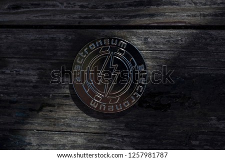 Electroneum cryptocurrency physical coin placed on the old wooden surface with the light shining through the gap