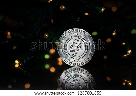 Electroneum cryptocurrency physical coin placed next to Christmas lights