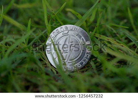Electroneum mobile cryptocurrency physical coin placed on the grass