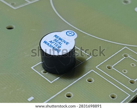 Electronic active buzzer component on PCB prototype board, macro concept for hardware manufacturing, circuit design, and alarm systems.