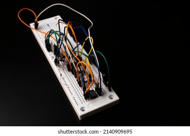 Electronic breadboard with resistor, transistir, wires on black background