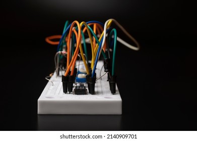 Electronic breadboard with resistor, transistir, wires on black background