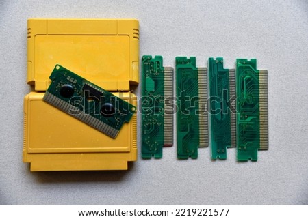 Electronic cartridge board for retro game console. A yellow plastic cartridge on a black background and an electronic board.Digital technology concept. Black background. Modern design.