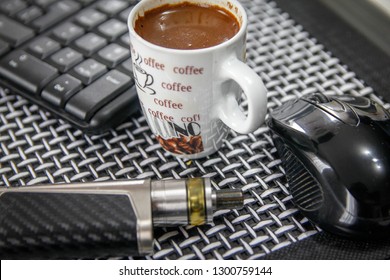 Electronic cigarette, cup of coffee, computer mouse and keyboard on table in living room