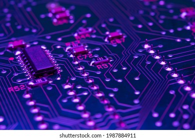 Electronic circuit board components chips resistors illuminated with neon light