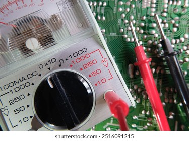 Electronic circuit testing. Electrical measuring instruments. Analog multimeter on the soldered electronic surface. Focused on the dial plate.