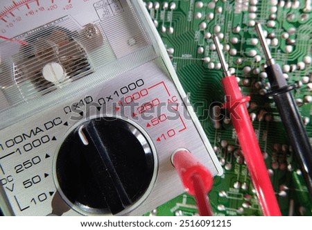 Electronic circuit testing. Electrical measuring instruments. Analog multimeter on the soldered electronic surface. Focused on the dial plate.