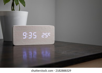 Electronic clock, indoor flower stand on the table show the time and temperature 