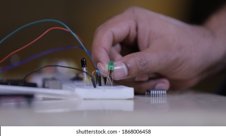 Electronic components connecting in Breadboard, a hand of technician holds led light