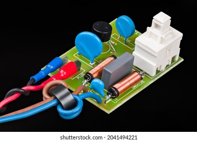 Electronic Components Of Electric Motor Supply Module On Black Background. Ferrite Beads And Inductors, Ceramic Filter Capacitors Or Connectors And On-off Switch On PCB. Electromagnetic Compatibility.