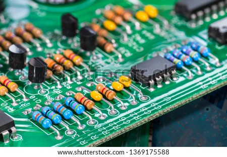 Electronic components. Integrated circuits, resistors, transistors and capacitors on PCB. Green copper board detail. Standard color code. Old computer hardware. Electrotechnology. Waste sorting. Eco.