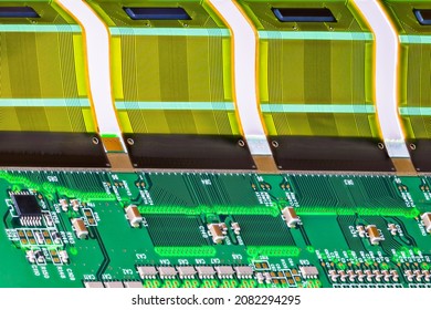 Electronic Components On Circuit Board With Printed Multi Wire Connections On Bent Flexible Part. Resistors, Capacitors And A Chip On Green PCB In Assembly With Plastic FPC Interface For A LCD Device.