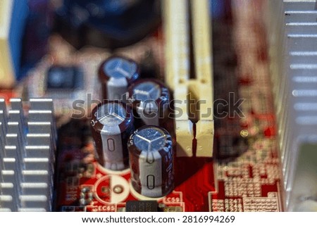 Electronic components on a red printed circuit board with capacitors and heat sink