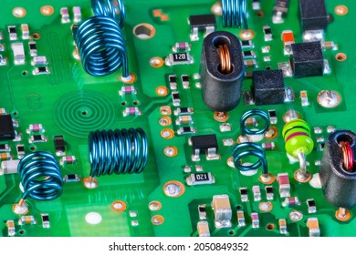 Electronic components to receiving radio-frequency signal on green printed circuit board. Planar spiral coil in PCB layer, air-core inductors and surface-mount devices inside RF module of TV receiver.