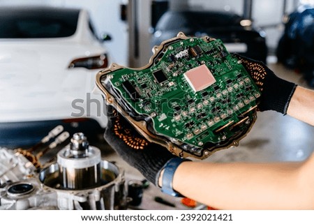 Electronic Control Unit (ECU) of modern electric car in male auto mechanic or car repairman hands. Motor inverter. Rear drive inverter module unit