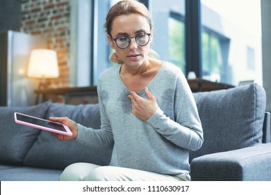 Electronic Correspondance. Troubled Mature Woman Using Tablet And Having Hot Flash