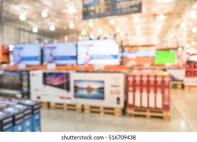 Electronic Department Store With Bokeh Blurred Background. Television Retail Shop, TVs Display On Shelf At Wholesale Store. Defocused Background Of Warehouse Interior Technology Aisle, Bokeh Lights.