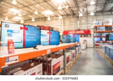 Electronic Department Store With Row Of TVs On Shelves Display. Television Retail Shop, TVs Shelf Wholesale Store. Defocused Warehouse Interior Technology Aisle, Inventory, Export, Business Concept.