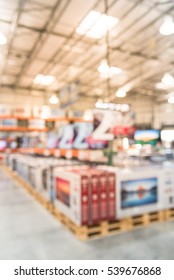 Electronic Department Store With Row Of TVs On Shelves Display. Television Retail Shop, TVs Shelf Wholesale Store. Defocused Warehouse Interior Technology Aisle, Inventory, Export, Business Concept.