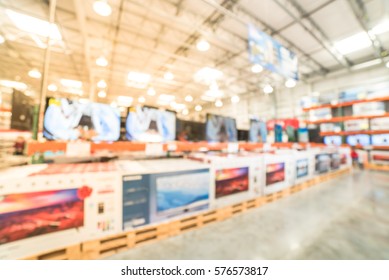 Electronic Department Store With Row Of TVs On Shelves Display. Television Retail Shop, TVs Shelf Wholesale Store. Defocused Warehouse Interior Technology Aisle, Inventory, Export, Business Concept.