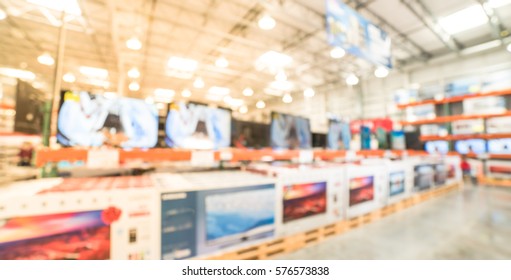 Electronic Department Store With Row Of TVs On Shelves Display. Television Retail Shop, TVs Shelf Wholesale Store. Defocused Warehouse Interior Technology Aisle, Inventory, Export. Panorama Style.