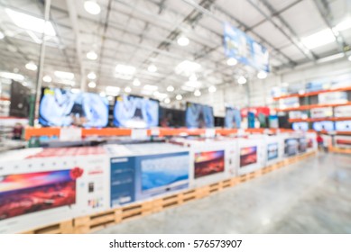 Electronic Department Store With Row Of TVs On Shelves Display. Television Retail Shop, TVs Shelf Wholesale Store. Defocused Warehouse Interior Technology Aisle, Inventory, Export, Business Concept.