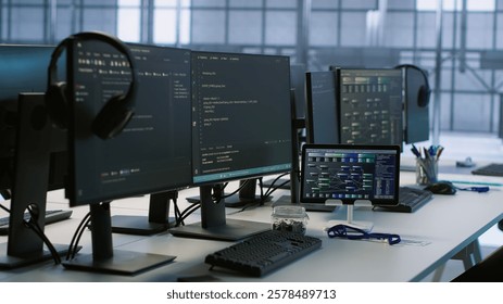 Electronic devices in empty data center establishment monitoring hardware energy consumption. PC monitors on desk used for checking potential system failures in server room, handheld camera shot
