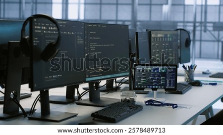 Electronic devices in empty data center establishment monitoring hardware energy consumption. PC monitors on desk used for checking potential system failures in server room, handheld camera shot
