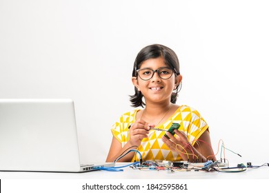 Electronic Experiment - Asian Indian Small Girl Student Performing Or Studying Science With Wires, Connections, Studying From Laptop Or Tablet Computer