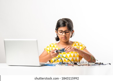 Electronic Experiment - Asian Indian Small Girl Student Performing Or Studying Science With Wires, Connections, Studying From Laptop Or Tablet Computer