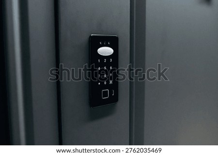 Electronic keypad access control system installed on a black wall, with numeric buttons and a fingerprint scanner for enhanced security measures