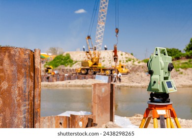 Electronic leveler device ensure precise measurements before undertaking large construction projects. Metal piles for bridge foundation along coast, across river is mobile crane    
