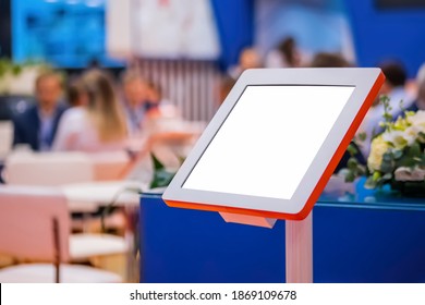 Electronic Multimedia Tablet Kiosk With Blank White Display At Exhibition, Trade Show, Conference - Close Up View. Mock Up, Futuristic, Corporate, Copyspace, Template, White Screen, Technology Concept