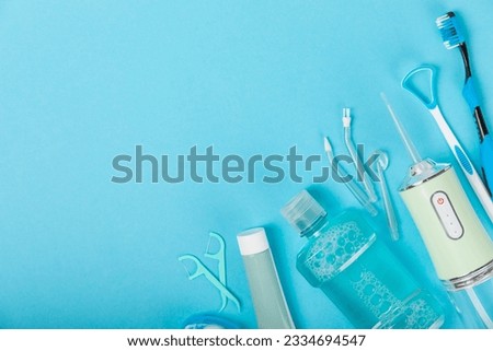 Electronic oral irrigator, toothbrush, paste, dental floss and mouthwash on a blue background. Dental tool for oral hygiene. Electric Interdental Cleaner. Dental water shower. Oral care concept. 