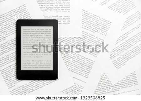Electronic reader with the screen on and a text on it, on sheets of paper with text printed on them. Concepts: reading and digital technology. Flat lay image with copy space.