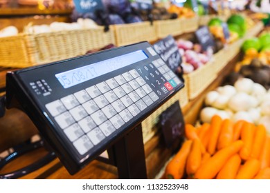 Electronic scales and control panel with a display on the counter of the vegetable market. Farm products and healthy food. Fruits and vegetables, trade. Soft focus.