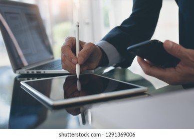 Electronic signature, Business and  technology concept. Businessman working on digital tablet signing contract with digital pen, holding mobile smart phone with laptop computer and business document