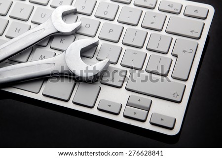 electronic technical support concept - spanners on computer keyboard