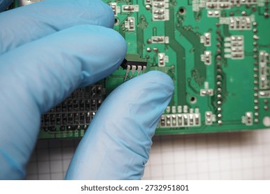 Electronic technician assembles an integrated circuit onto circuit board. Semiconductors in electronics.